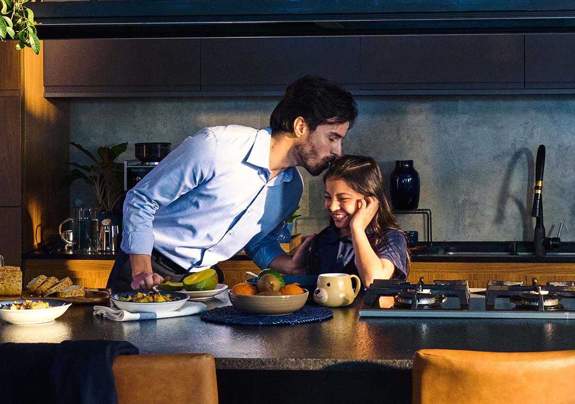 Pai beijando a testa da filha na cozinha